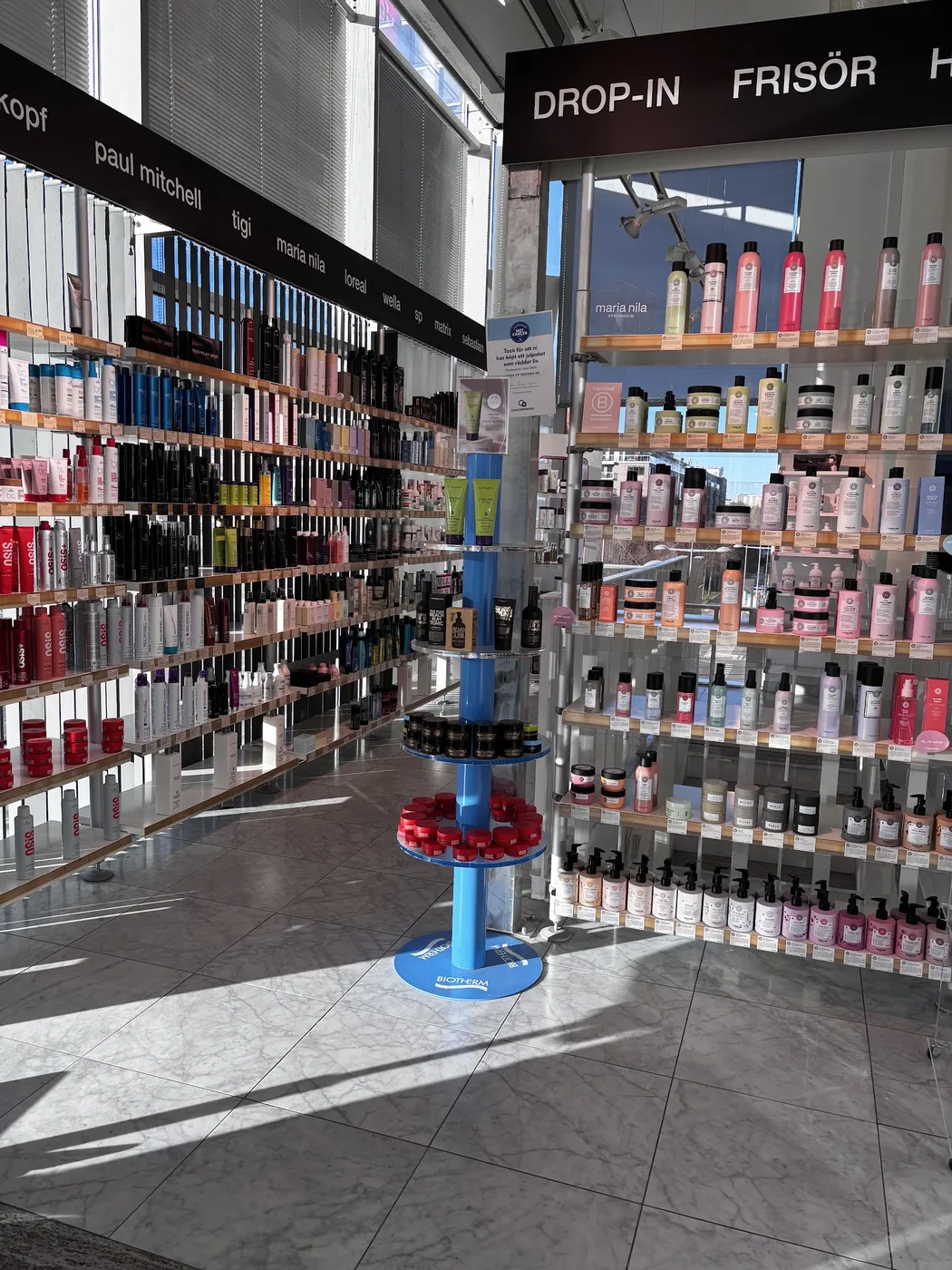 Butikens hyllor med schampo, balsam och stylingprodukter vid drop-in-skylten